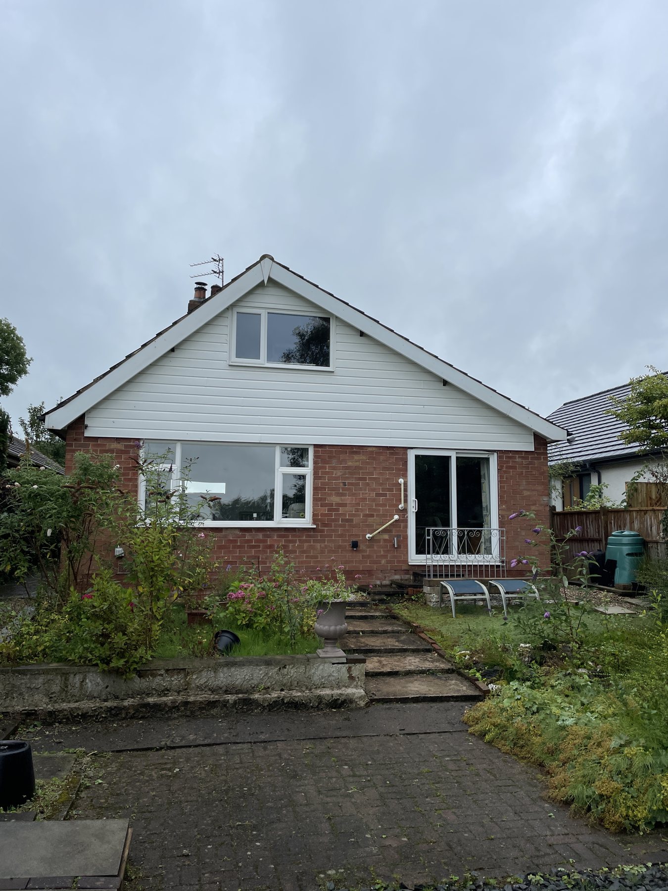 Brick chalet bungalow with a white gable overlooking a garden